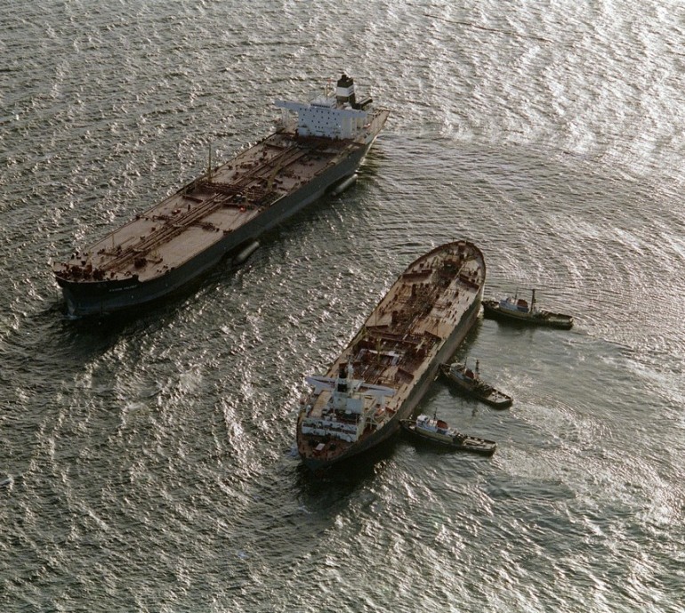 Three tugboats (R)  push the oil tanker Exxon San